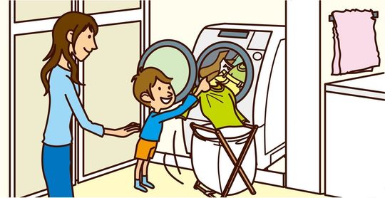 洗濯機に服を入れる男の子と見守るお母さん